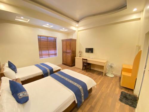 a bedroom with two beds and a desk in it at Rose Hotel in Hai Phong
