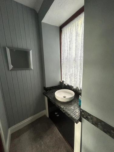a small bathroom with a sink and a window at Bronallt in Barmouth