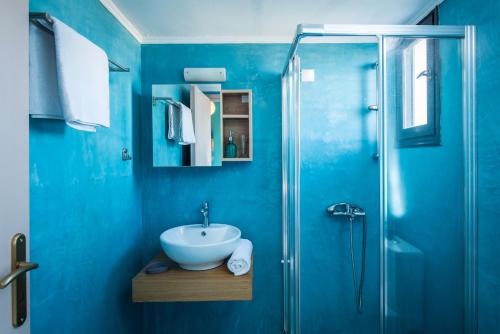 a blue bathroom with a sink and a shower at Anemos Inn by Estia in Kokkíni Khánion