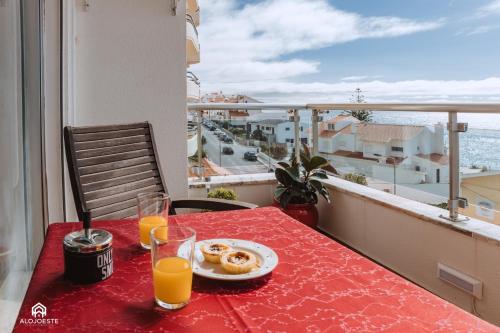 a table with a plate of food and two glasses of orange juice at Studio L - Ericeira in Ericeira