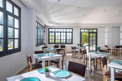 a dining room with tables and chairs and windows at Anemos Inn by Estia in Kokkíni Khánion