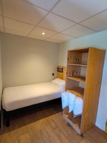 a small room with a bed and a book shelf at greet hotel Castets Coeur des Landes in Castets