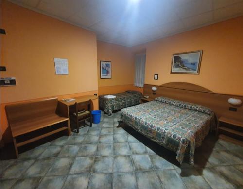 a hotel room with two beds and a desk at Hotel Azalea in Baveno