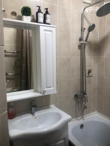 a bathroom with a sink and a shower with a mirror at at HOME in Prigorodnyy
