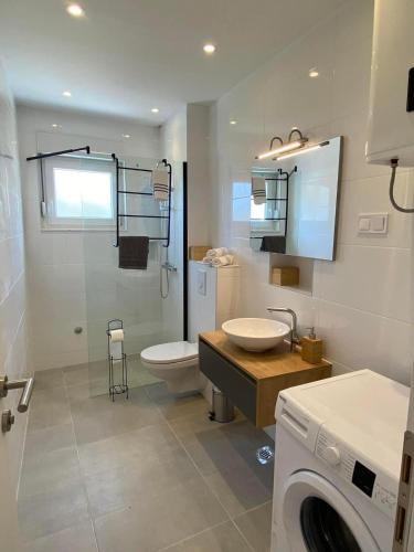 a bathroom with a toilet sink and a washing machine at Apartmani Marko in Trogir