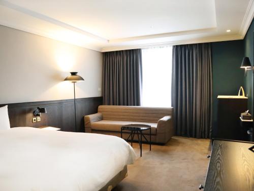 a hotel room with a bed and a couch at Maison Glad Jeju in Jeju