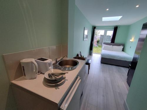 a kitchen with a sink and a couch in a room at Letzi Ensuite, 15 Min to Heathrow, Fast WiFi in Hayes