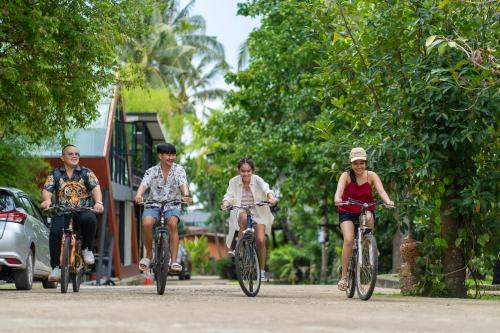 a group of people riding bikes down a street at Kaengkrachan Boathouse Paradise Resort in Kaeng Krachan