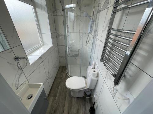 a white bathroom with a toilet and a sink at Letzi Ensuite, 15 Min to Heathrow, Fast WiFi in Hayes