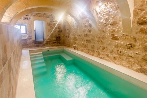 a pool of water in a room with a stone wall at Naduri, Beautiful Gozitan Villa plus Pool - Happy Rentals in Nadur