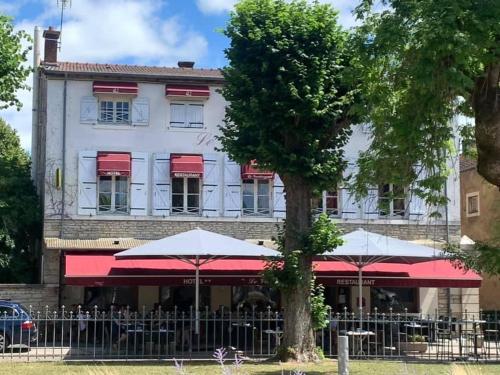 a white building with red awnings and a tree at Le Vendangerot in Rully