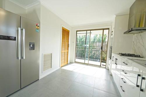 a kitchen with a refrigerator and a large window at Maroondah 3BR Brick Entire Home Free Wi-Fi Parking in Ringwood