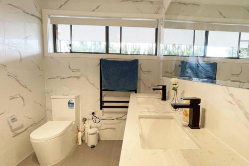 a white bathroom with a toilet and a sink at Maroondah 3BR Brick Entire Home Free Wi-Fi Parking in Ringwood