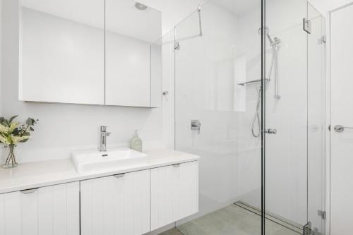 y baño blanco con lavabo y ducha. en Urban Rest Neutral Bay Apartments en Sídney