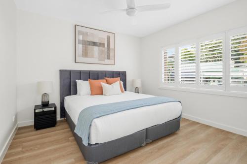 a white bedroom with a large bed with orange pillows at Urban Rest Neutral Bay Apartments in Sydney