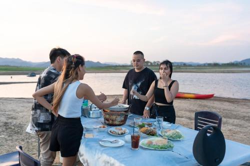 a group of people standing around a table on the beach at Kaengkrachan Boathouse Paradise Resort in Kaeng Krachan