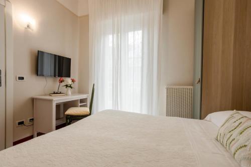 a bedroom with a bed and a desk and a television at Villa Arizona in Milano Marittima