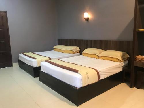 two twin beds in a room with at Baiduri's Place in Pantai Cenang