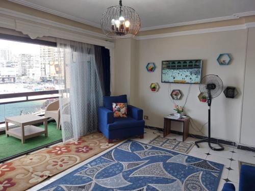 a living room with a blue chair and a large window at شقة فندقية علي البحر مباشرة بجليم in Alexandria