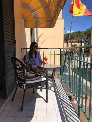 a woman sitting at a table under an umbrella at Hotel La Barcarola in Marina di Campo