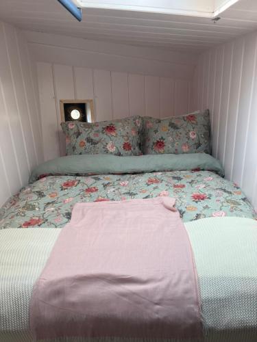 een kleine slaapkamer met een bed met een bloemendeken bij Skinny Bridge Houseboat Amstel View Amsterdam in Amsterdam
