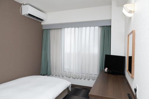 pokój hotelowy z łóżkiem i oknem w obiekcie Heiwadai Hotel Tenjin w mieście Fukuoka