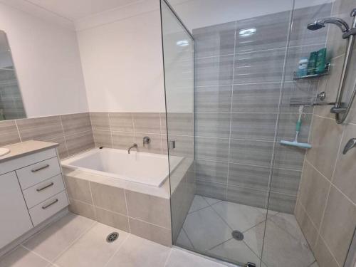 a bathroom with a shower and a tub and a sink at Glass House Mountains Retreat in Beerwah