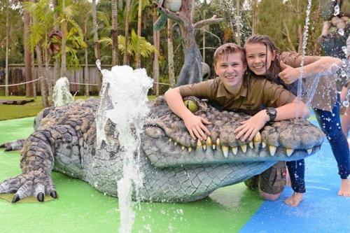 two girls are riding on a fakeigator in a water park at Glass House Mountains Retreat in Beerwah
