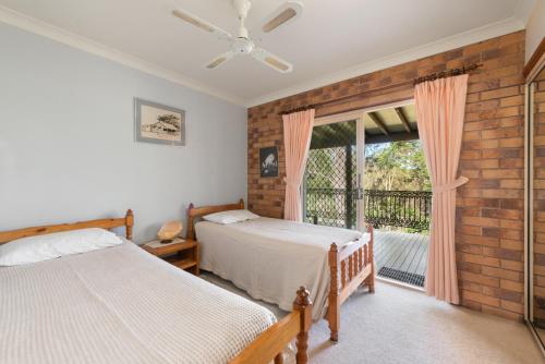 a bedroom with two beds and a window at Coucals Cottage in Mount Crosby