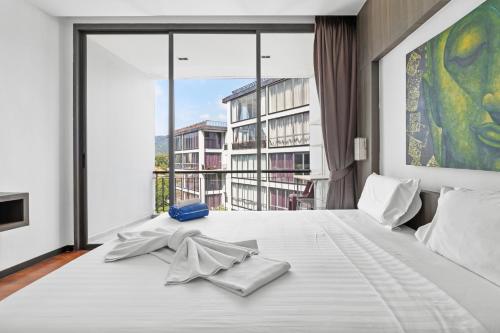 Un dormitorio con una cama blanca con una ventana grande. en Icon Park Apartments - Kamala Beach, en Kamala Beach