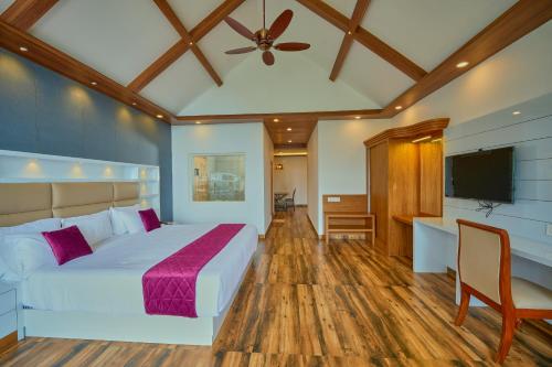 a bedroom with a bed and a flat screen tv at The Planet Munnar in Suryanelli