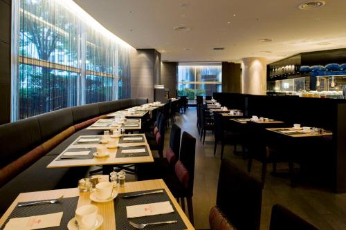 a dining room with long tables and chairs and windows at ANA Crowne Plaza Kanazawa by IHG in Kanazawa