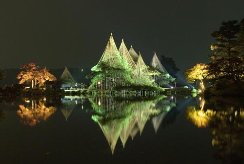 a building with lights on the water at night at ANA Crowne Plaza Kanazawa by IHG in Kanazawa