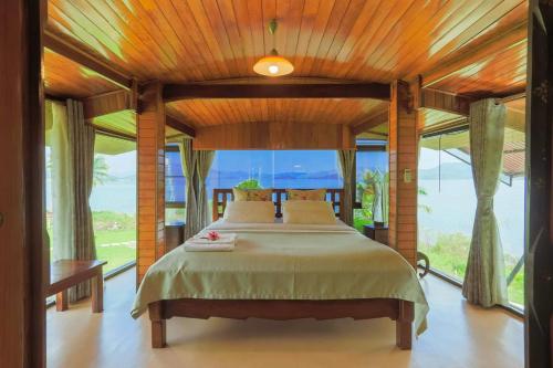 a bedroom with a large bed with a large window at Kaengkrachan Boathouse Paradise Resort in Kaeng Krachan