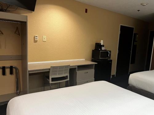 a bedroom with a desk and a bed and a microwave at Microtel Inn & Suites by Wyndham Houston/Webster/Nasa/Clearlake in Nassau Bay