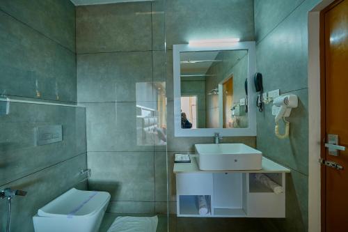 a bathroom with a sink and a toilet and a mirror at The Planet Munnar in Suryanelli