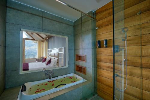 a bathroom with a tub and a shower with a mirror at The Planet Munnar in Suryanelli