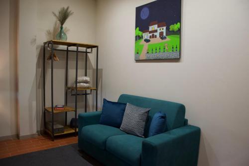 a living room with a blue couch and a painting at Casa M Tuscany in Chianciano Terme