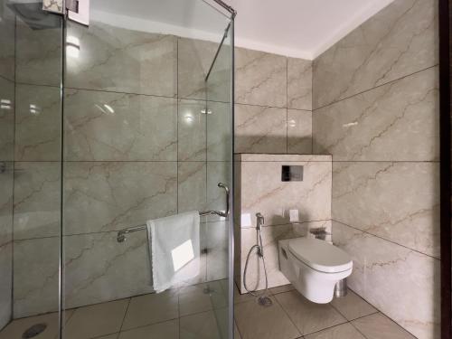 a bathroom with a glass shower and a toilet at Pride Premier Solitaire in Dehradun