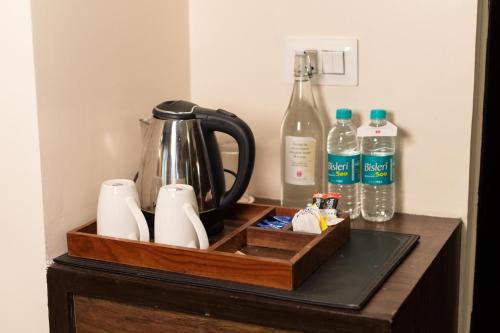 a wooden tray with a tea kettle and bottles of water at Pride Premier Solitaire in Dehradun