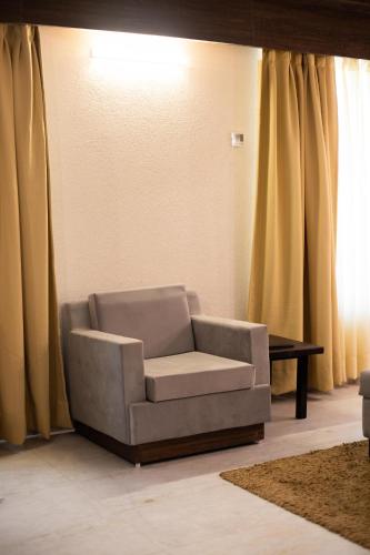 a living room with a chair and a table at Pride Premier Solitaire in Dehradun