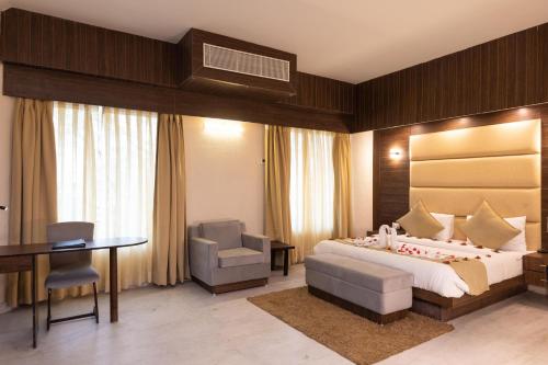 a bedroom with a bed and a desk and a chair at Pride Premier Solitaire in Dehradun