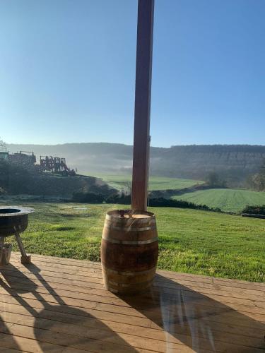 a barrel sitting on a deck with a view of a field at Gîte de l’Ambiance in Francheville
