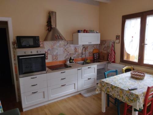 cocina con armarios blancos y mesa con microondas en La casa di Pia en Càbras