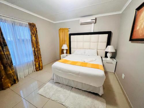 a bedroom with a large bed and a large window at GoldenWays Apartments in Mbabane