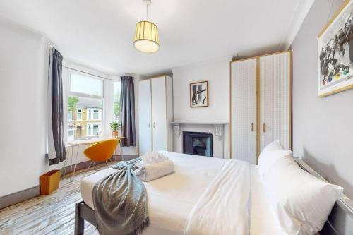una camera con letto bianco e camino di Enchanting 3 bedroom house with garden in Leyton a Londra