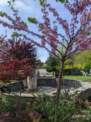 a garden with a fountain and a tree with pink flowers at Casa Rural Bilbao Caserio Gondra Alquiler Habitaciones in Mungia