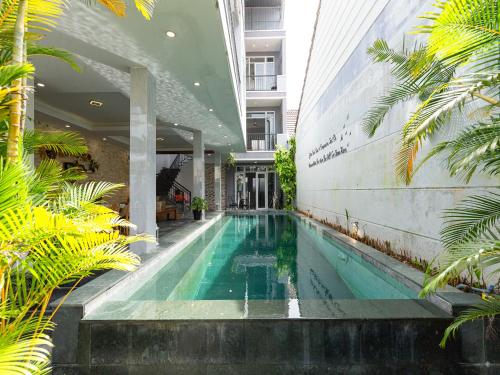 a swimming pool in the middle of a building with palm trees at HA Hero Hoian Pool House in Hoi An