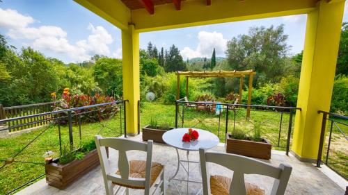 a patio with a table and chairs and a view of a garden at Zen Stone House in Agios Georgios Pagon