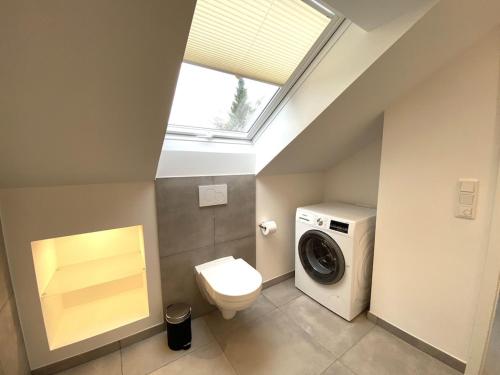 ein Badezimmer mit einem WC und einer Waschmaschine in der Unterkunft Moderne, hochwertig ausgestattete Hausscheibe in Sackgassenlage! in Westerholz
